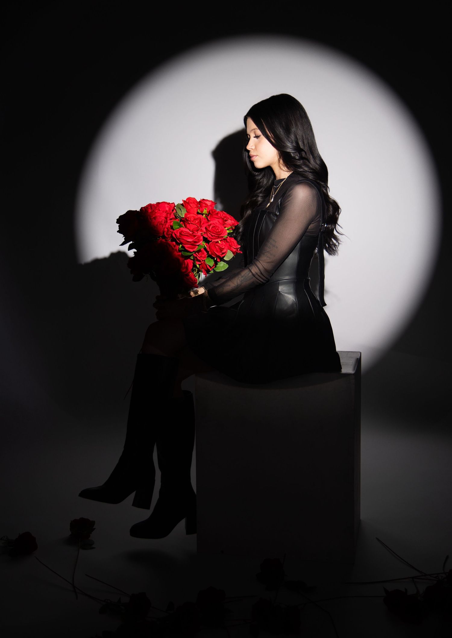 Dramatic black and white portrait with red roses and spotlight effect.