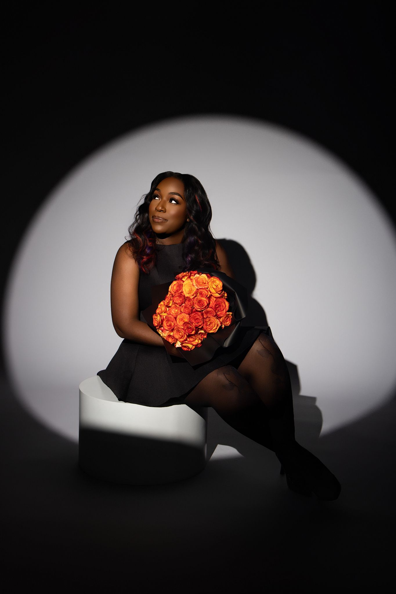 Dramatic black and white portrait series featuring a figure holding vibrant orange roses against a dark background.