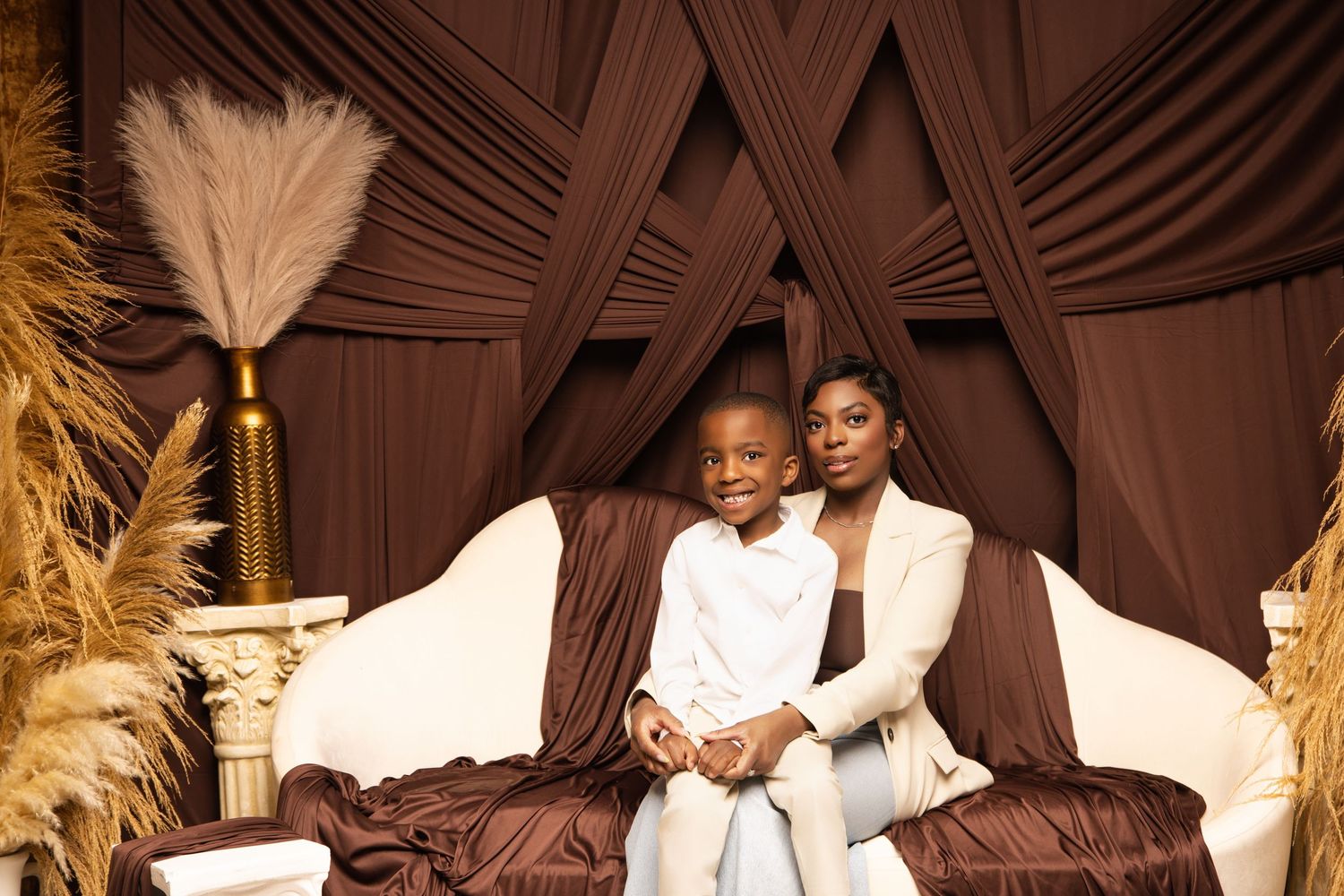 Romantic photoshoot with pampas grass decorations and brown fabric backdrop.