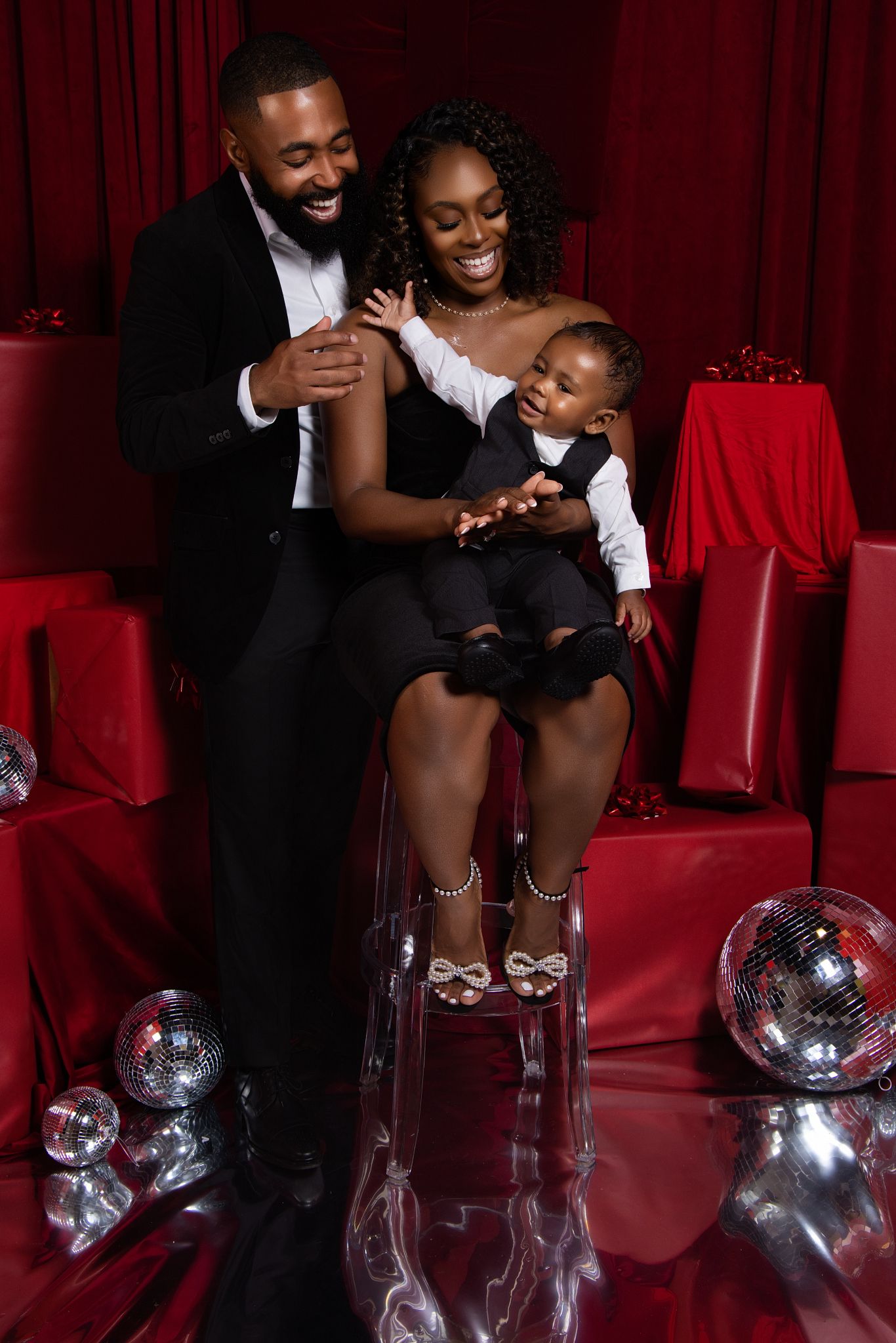 A family shares joyful moments together on red theater seats with disco balls in the background.