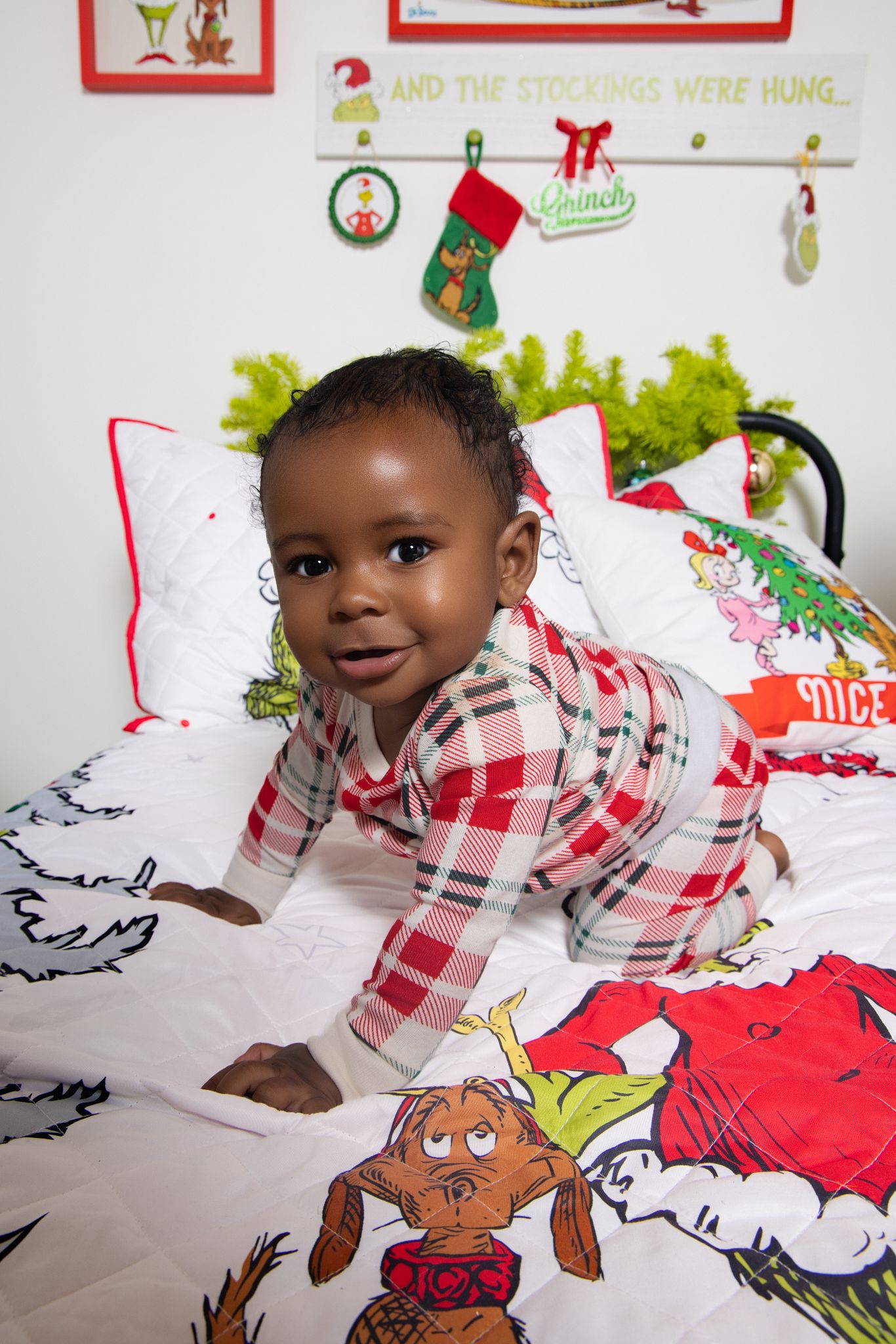 A child lies on a white surface with colorful holiday drawings and decorations visible in the background.