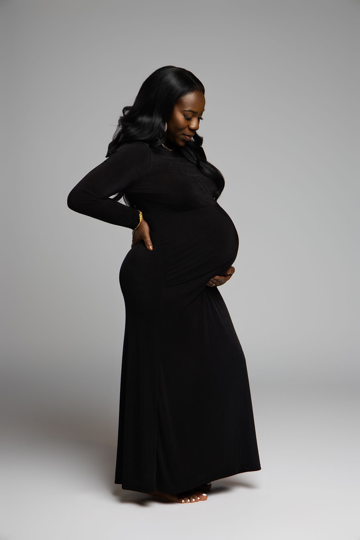 A figure in a flowing black dress poses expressively against a light gray background in a series of artistic movements.