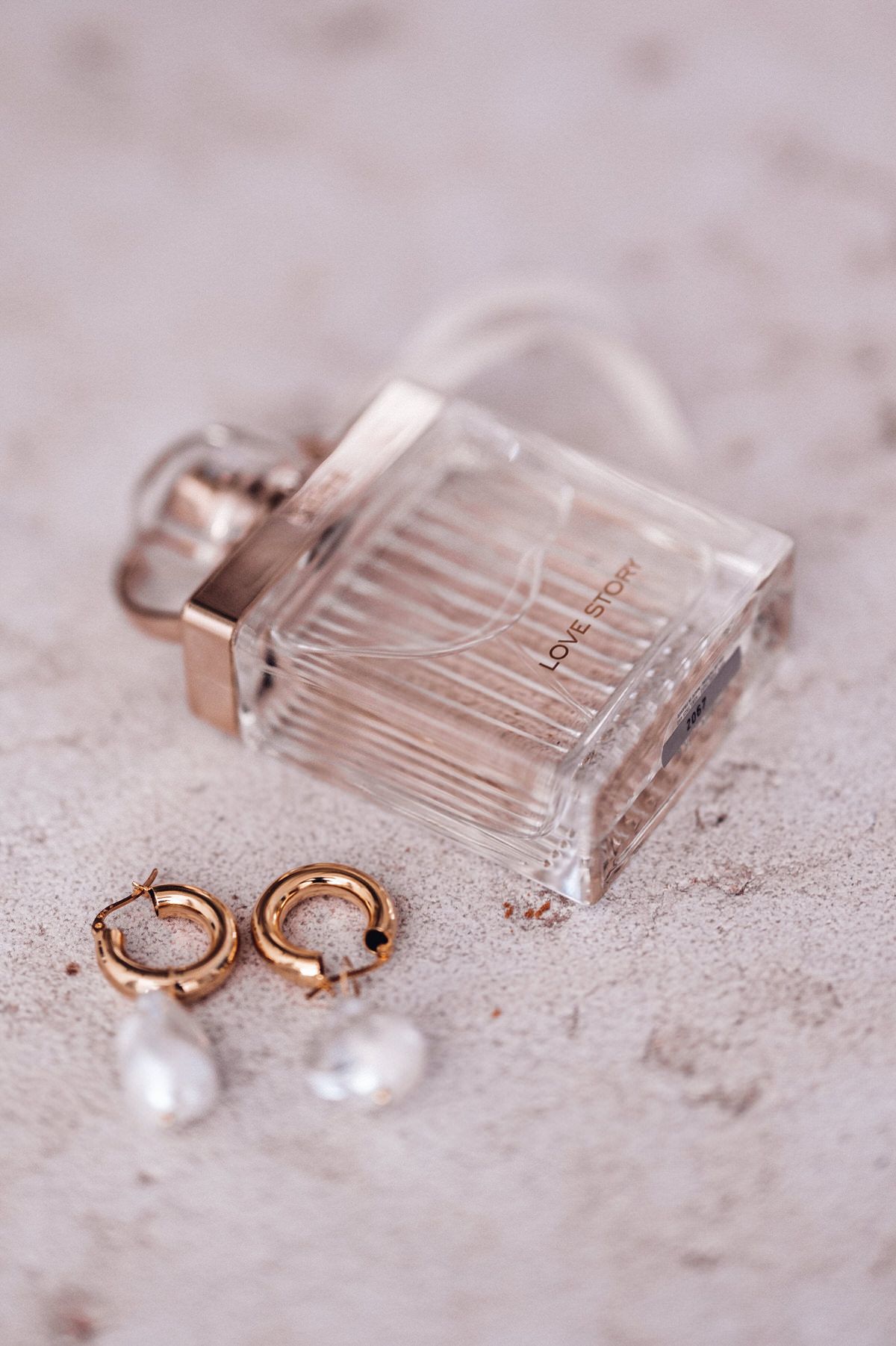 Wedding perfume and rings styled on a neutral surface, elegant bridal detail flatlay