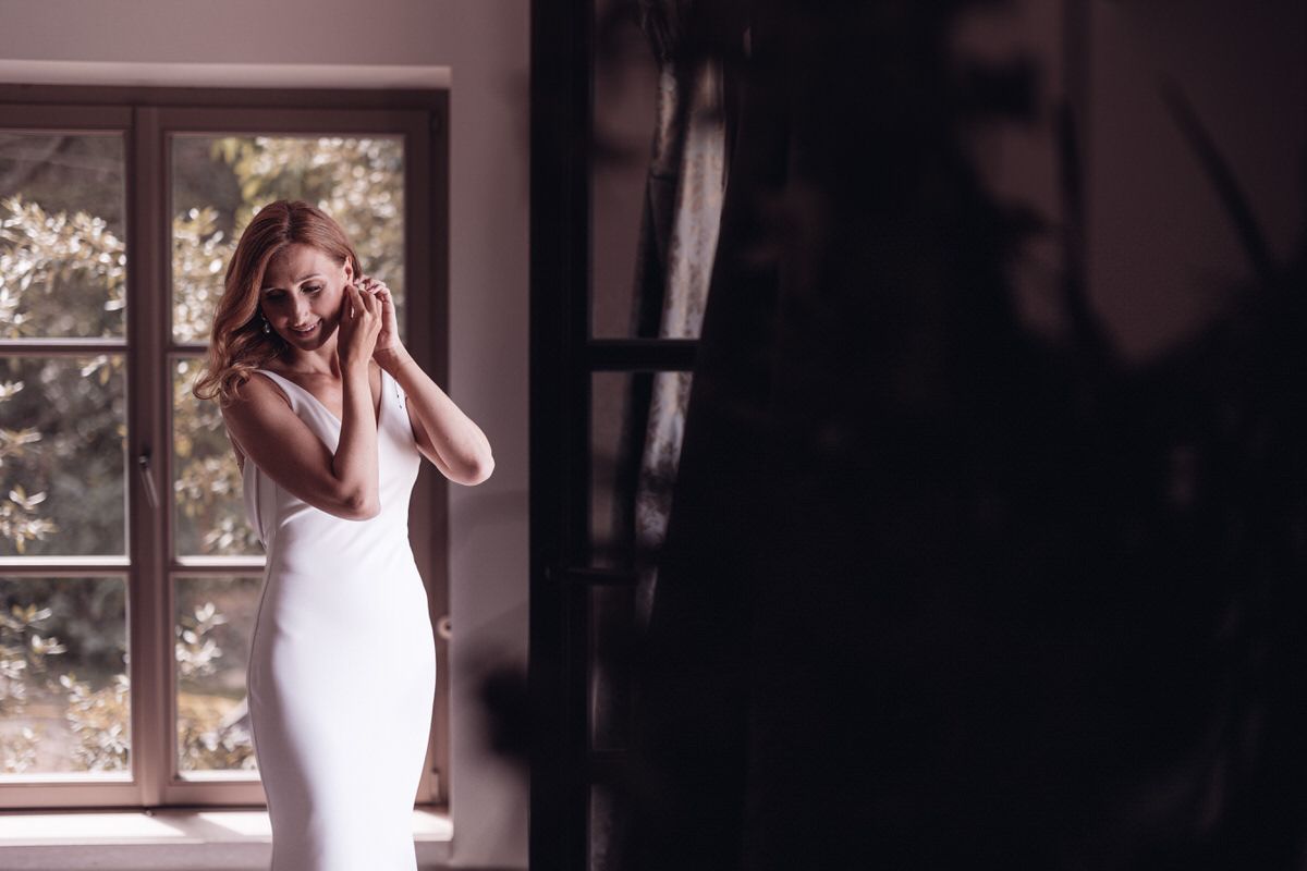 Bride reflected in a mirror adjusting her dress, emotional getting ready moment