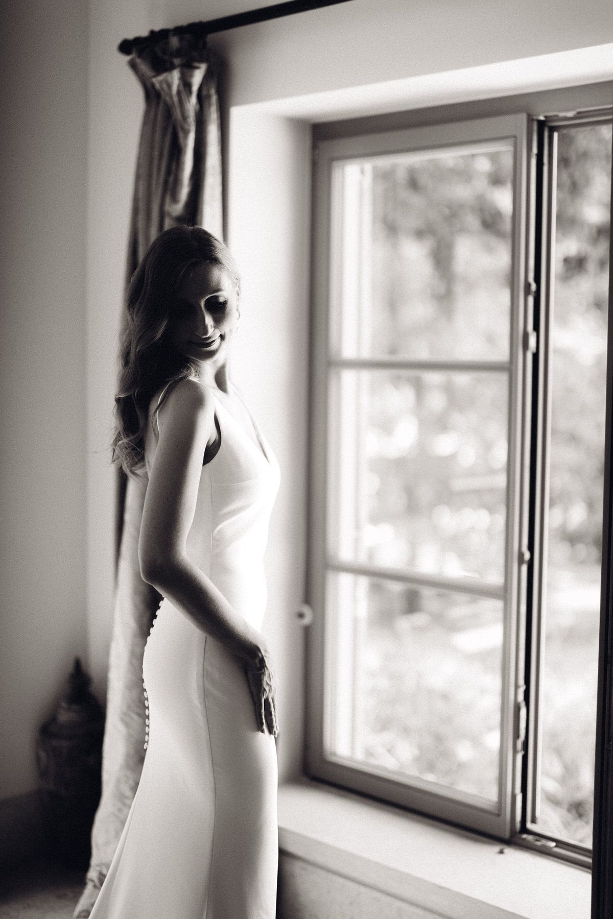 Bride posing by the window in black and white, classic and elegant wedding portrait