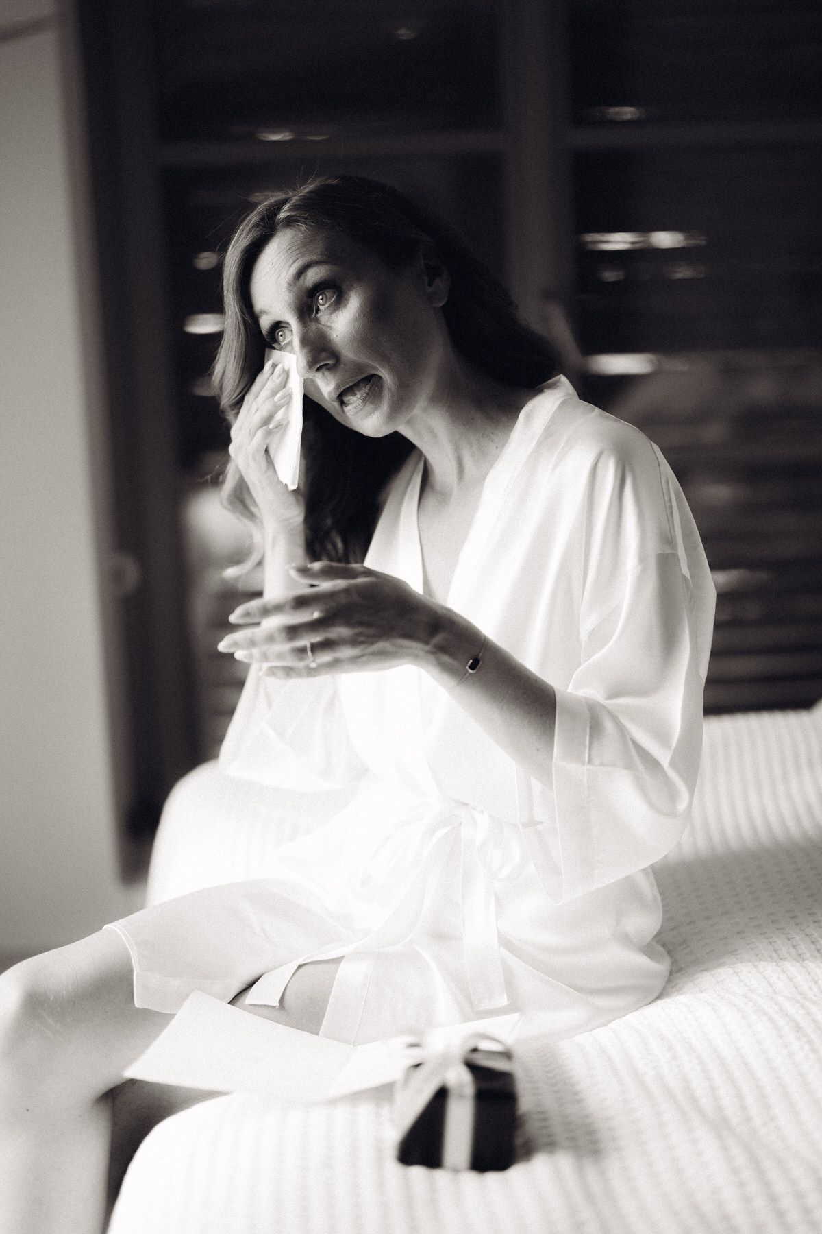 Bride smiling while holding champagne, relaxed and joyful wedding preparation moment