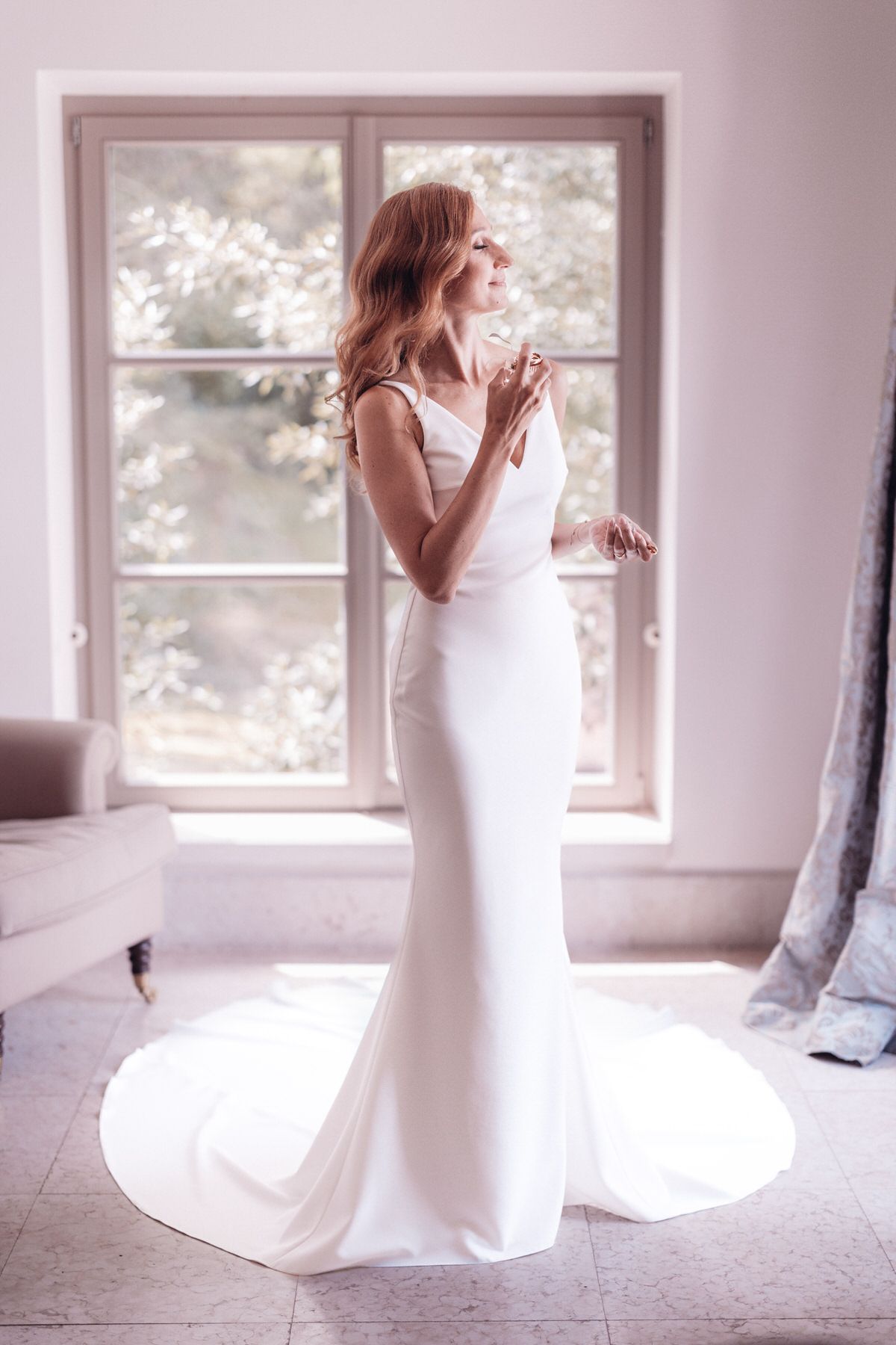 Bride standing in her wedding dress by the window, timeless and minimal bridal portrait