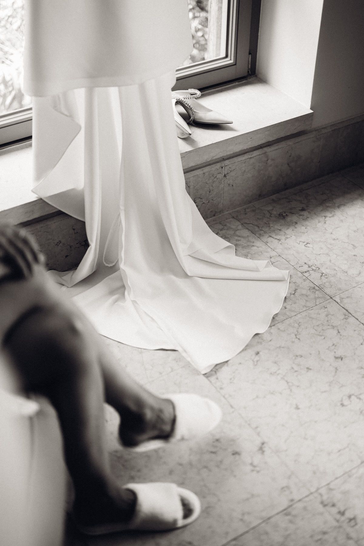 Bride’s dress flowing over the floor, soft textures and calm bridal preparation atmosphere