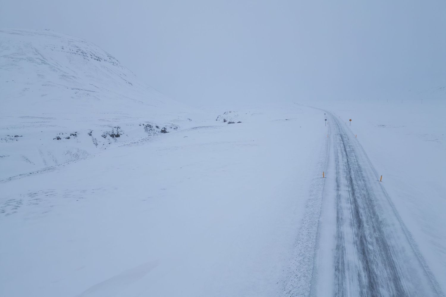 Snow-covered road winding through a white winter landscape.