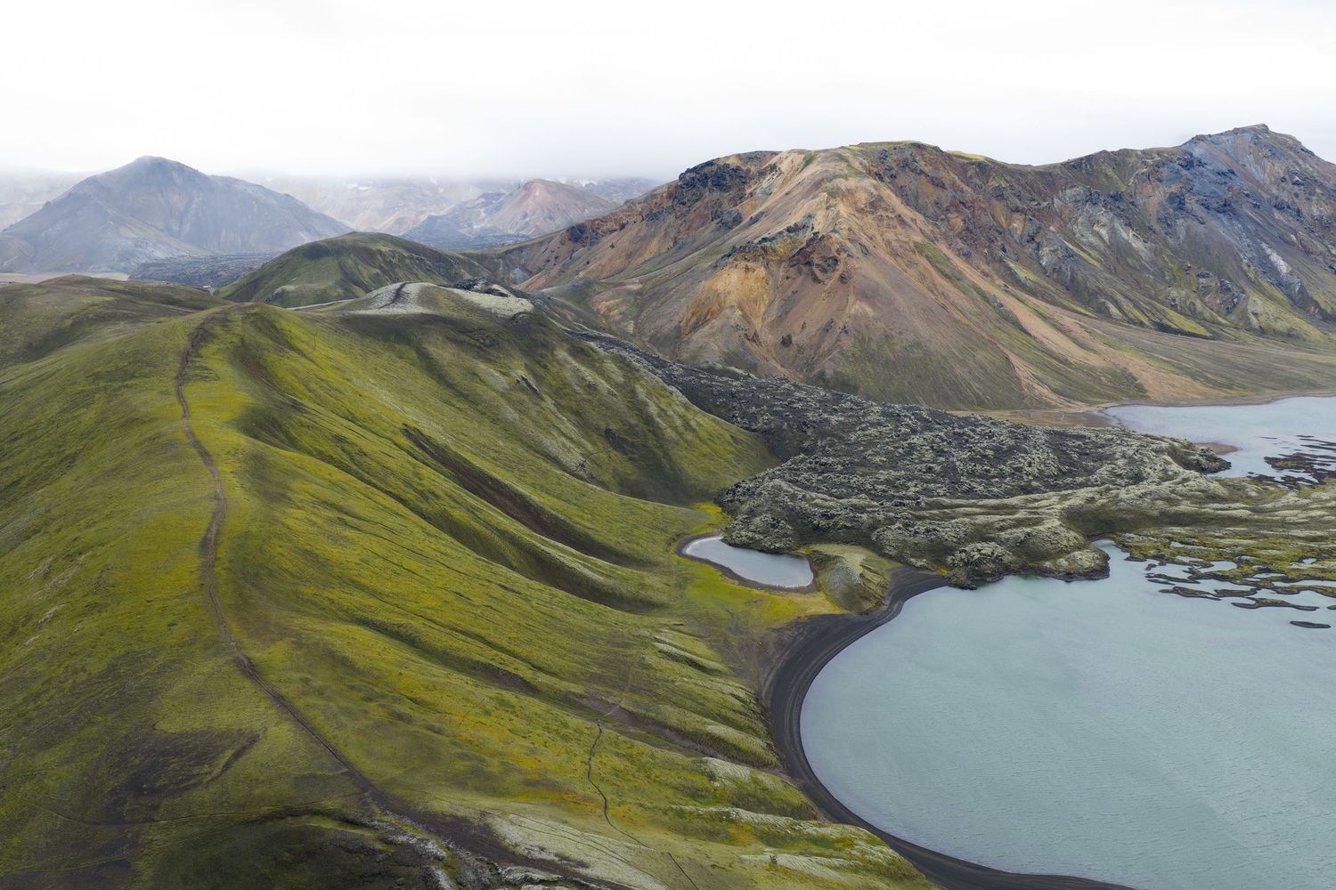 Alpine lakes nestled between green mountains under cloudy skies in a wilderness landscape.