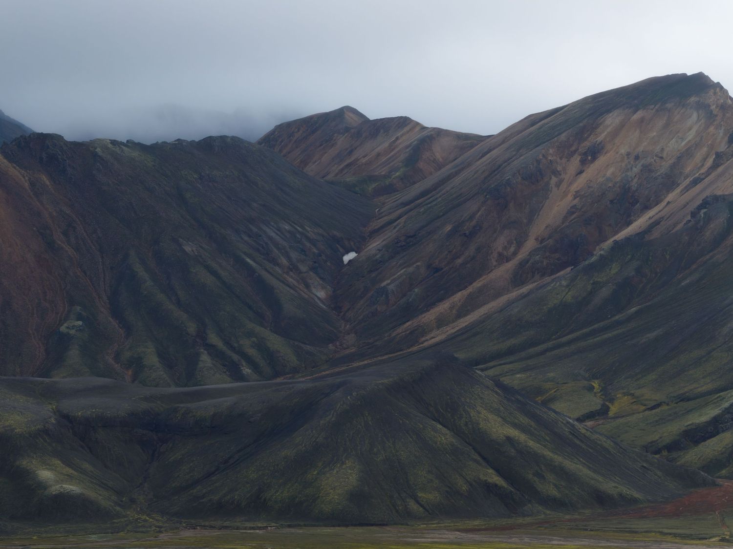 Cloudy mountain range with dramatic peaks and valleys stretching into the distance.