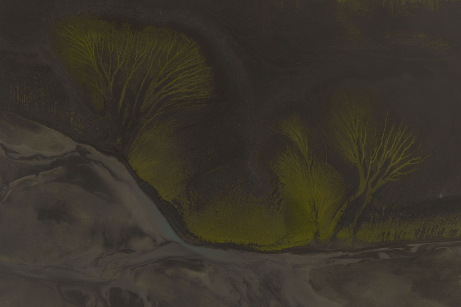 Moody aerial view of dark mountains with glacial rivers winding through the terrain.