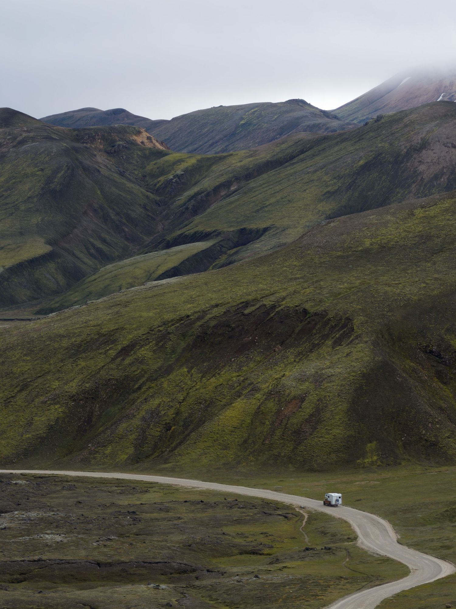 Winding mountain road curves through rugged Alaskan wilderness terrain.