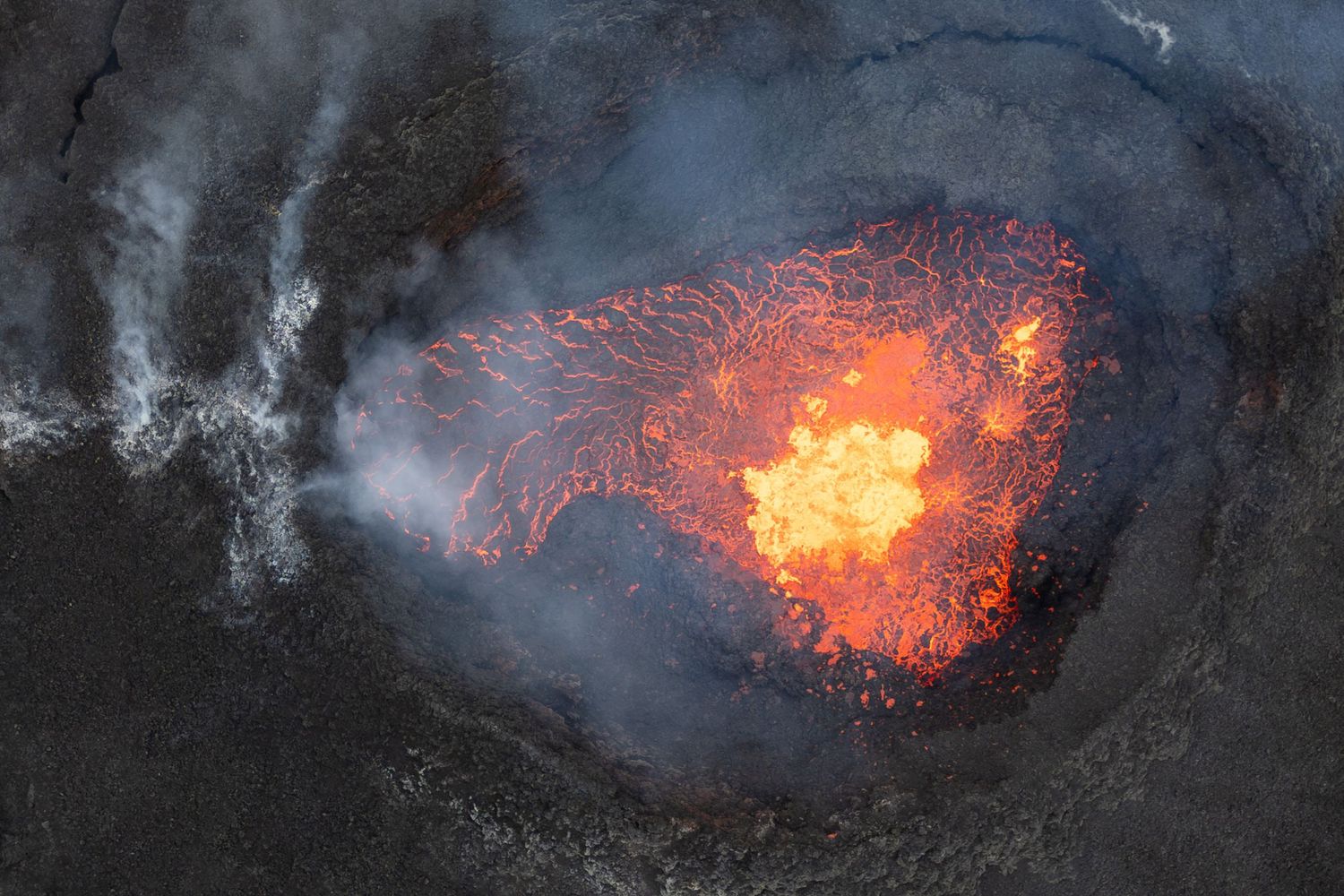 Active volcanic crater glowing with bright orange lava at night.