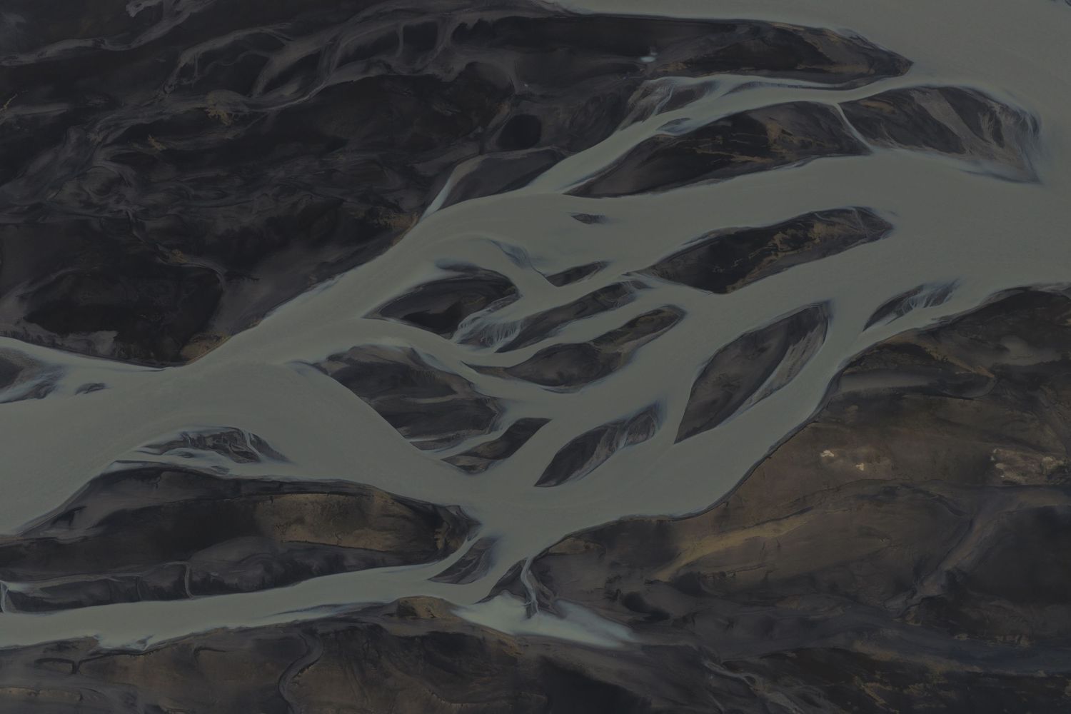 Rugged mountain landscape with braided glacial rivers flowing through a remote valley.