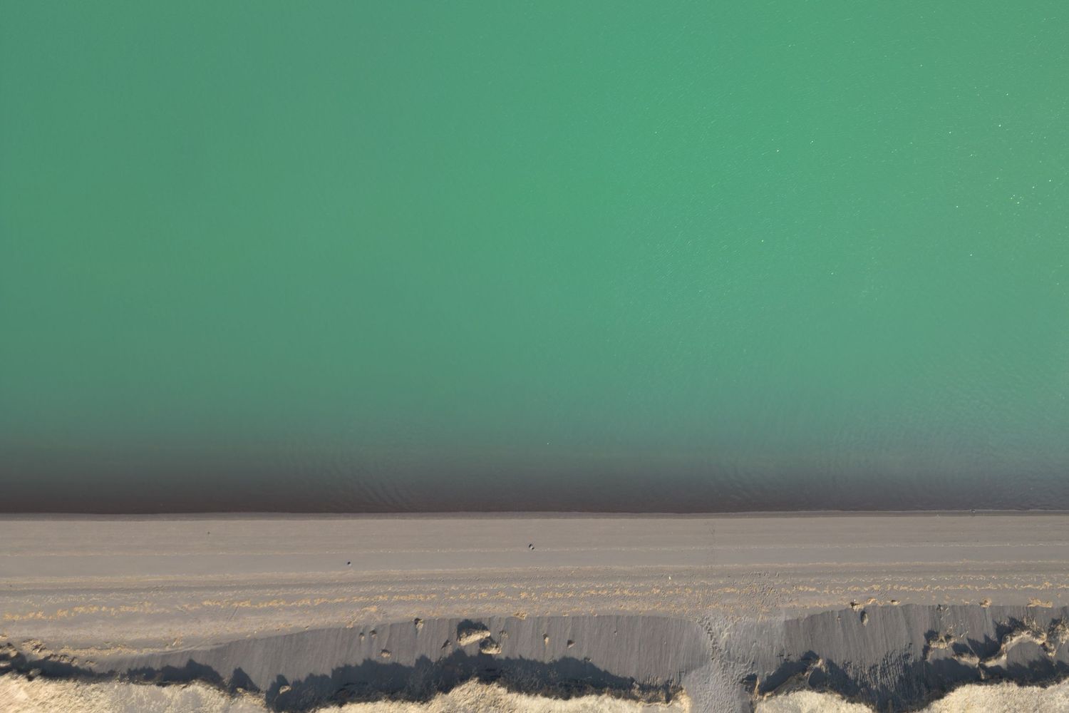 Desert landscape with flat sandy terrain against a bright green sky.