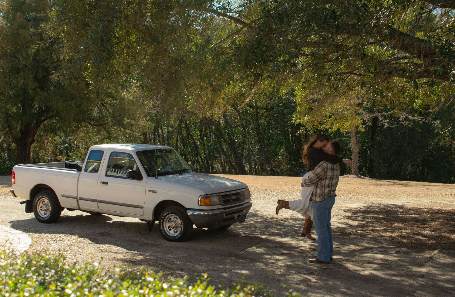 Cars parked in a shaded parking area surrounded by trees and greenery.