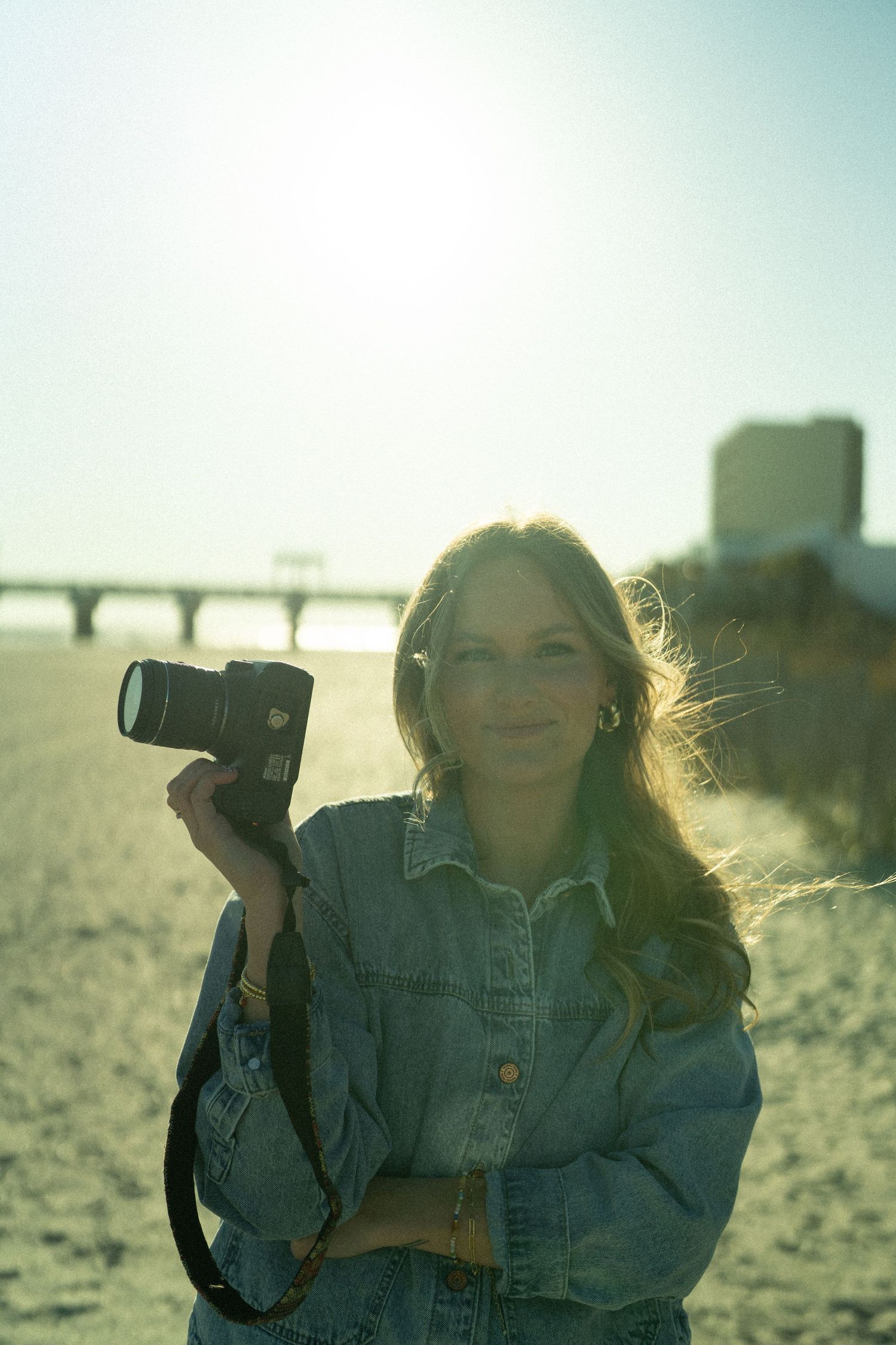 Photographer with camera on beach during golden hour.