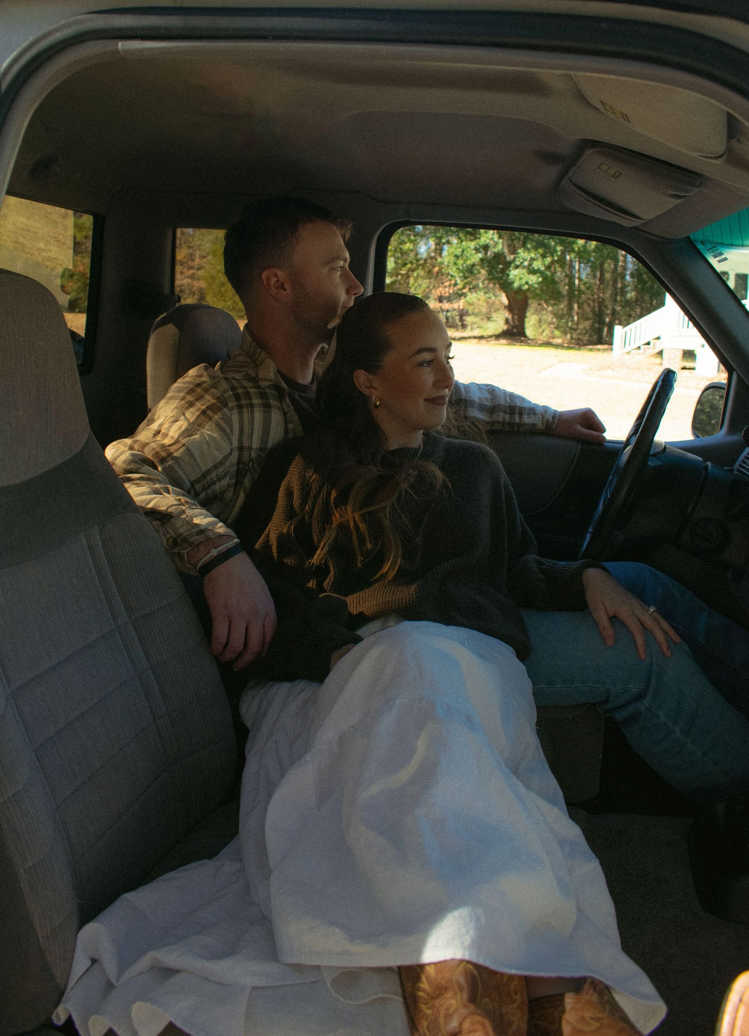 Interior view of people sitting in the back seat of a car with white fabric visible.