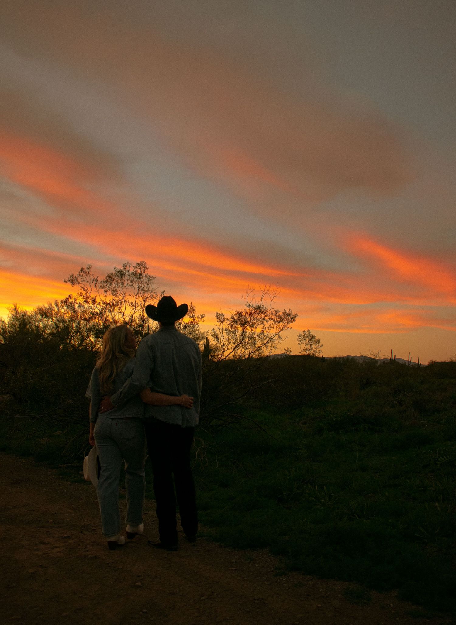 People and a horse silhouetted against a desert mountain landscape.