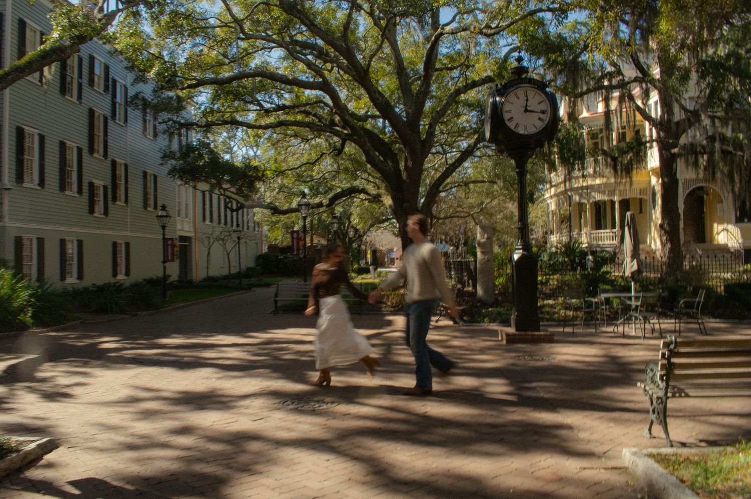 Tree-lined pathway with historic buildings and dappled sunlight.