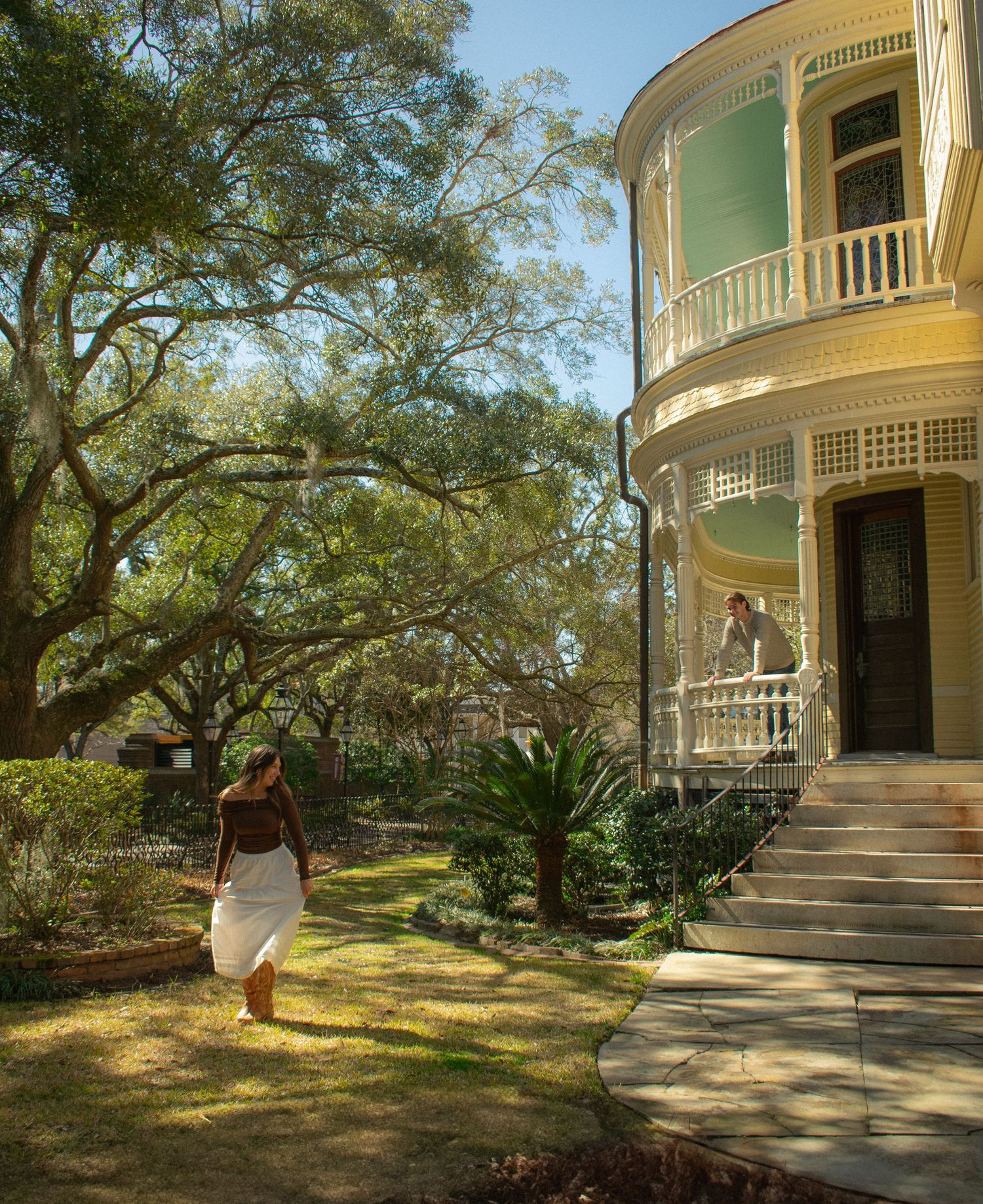 Colonial style house with curved porch and ornate architectural details in sunlight.