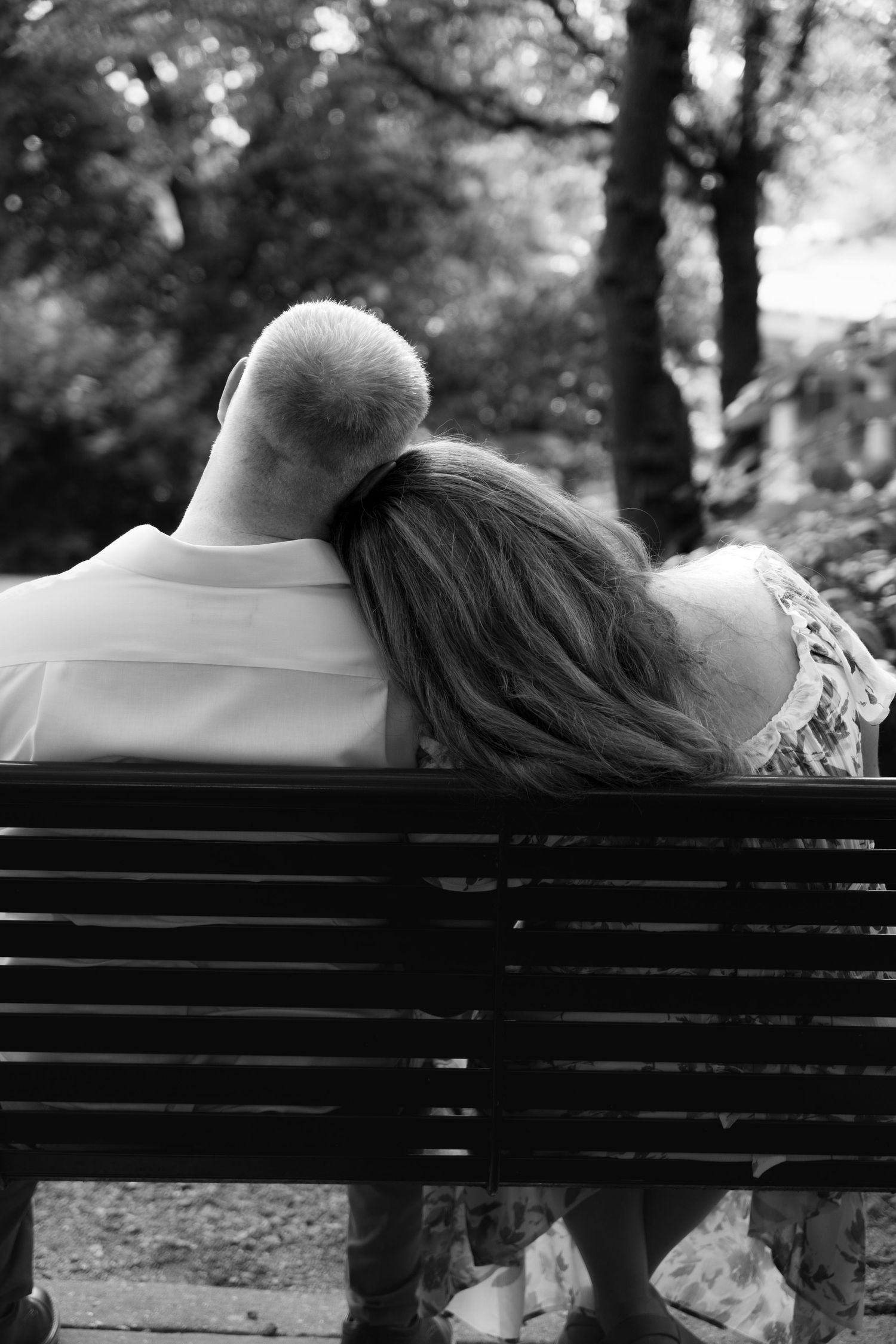 Bride to be lays head on fiancé sitting next to a bench, engagement photos, houston, tx