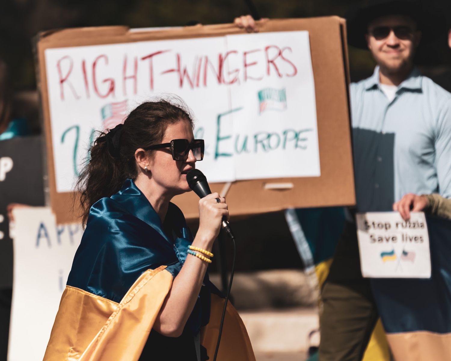 Protesters holding cardboard signs at a demonstration. Captured by a Seguin photographer at grain n glass