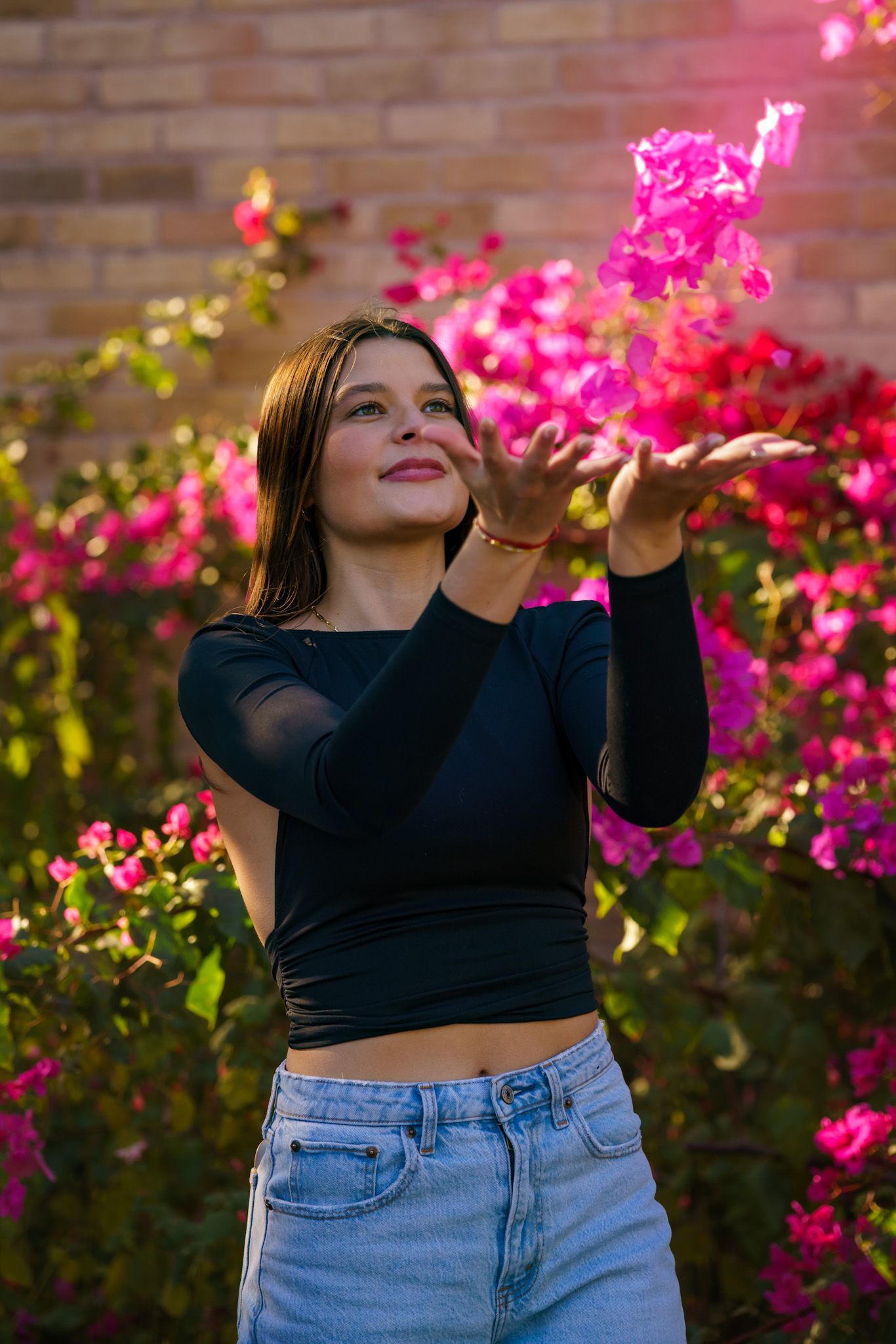 Person in black crop top posing against vibrant pink bougainvillea flowers. Captured by a Seguin photographer at grain n glass