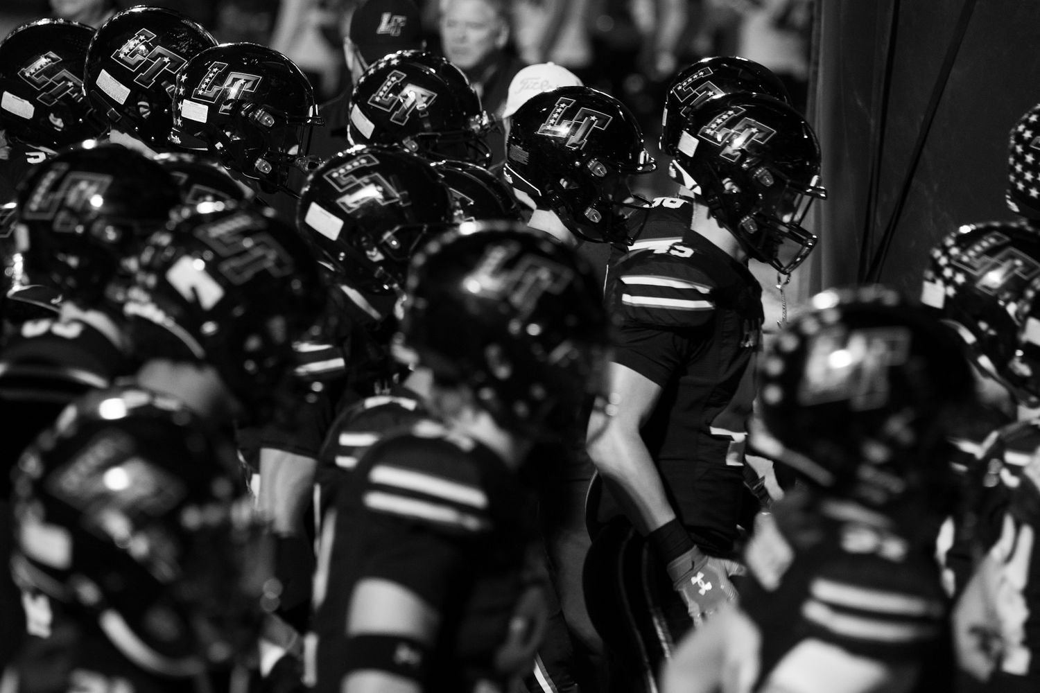 Black and white image of football players warming up. Captured by a Seguin photographer at grain n glass