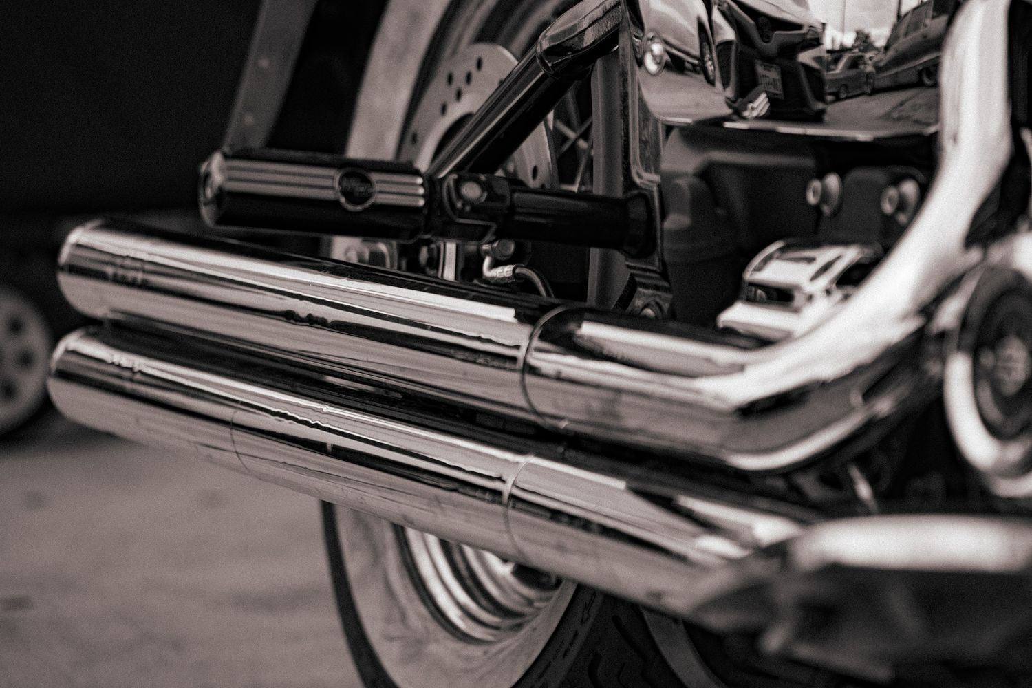 Close-up detail of chrome motorcycle exhaust pipes and engine parts in black and white. Captured by a Seguin photographer at grain n glass