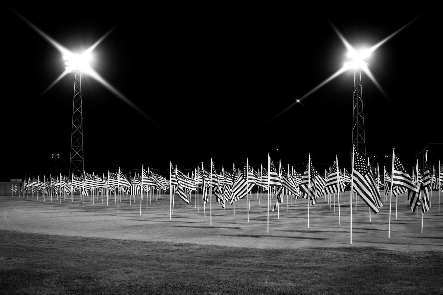 Rows of illuminated flags create a dramatic nighttime display in a memorial field. Captured by a Seguin photographer at grain n glass