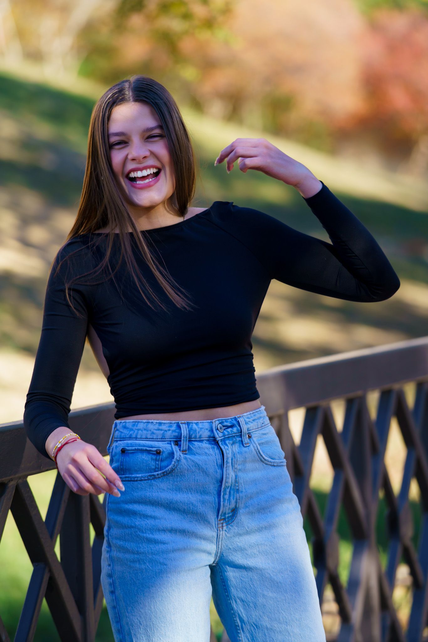 Casual outdoor fashion shoot featuring denim and black top against wooden railing. Captured by a Seguin photographer at grain n glass