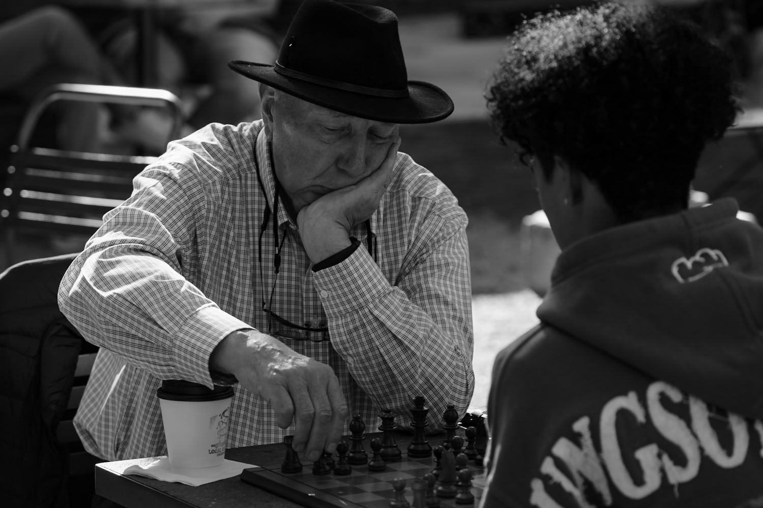 People sitting at a table playing chess in a casual outdoor setting. Captured by a Seguin photographer at grain n glass
