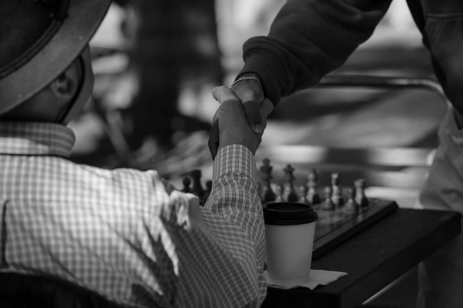 Young and old Chess players shaking hands before match. Captured in monochrome by a Seguin photographer at grain n glass