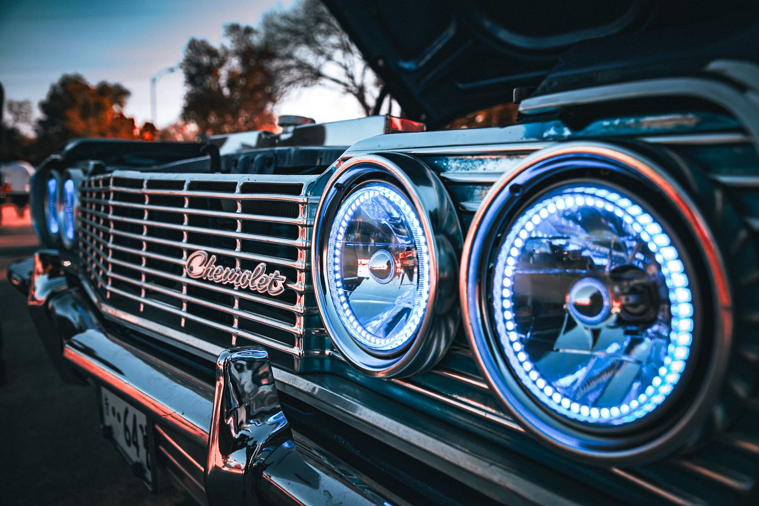 Blue illuminated headlights and chrome grille of classic car in dramatic lighting. Captured by a Seguin photographer at grain n glass