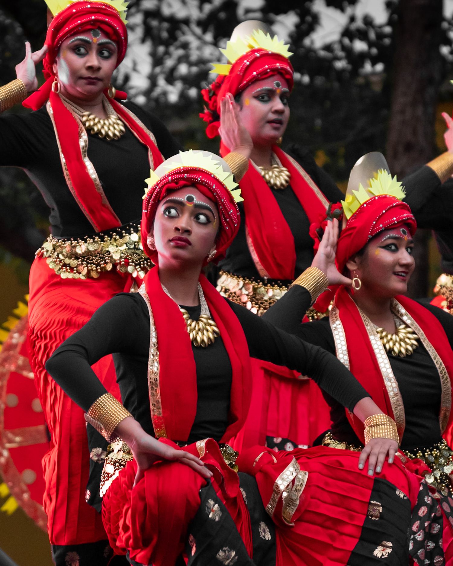 Group of dancers in red and black costumes perform synchronized traditional movements.