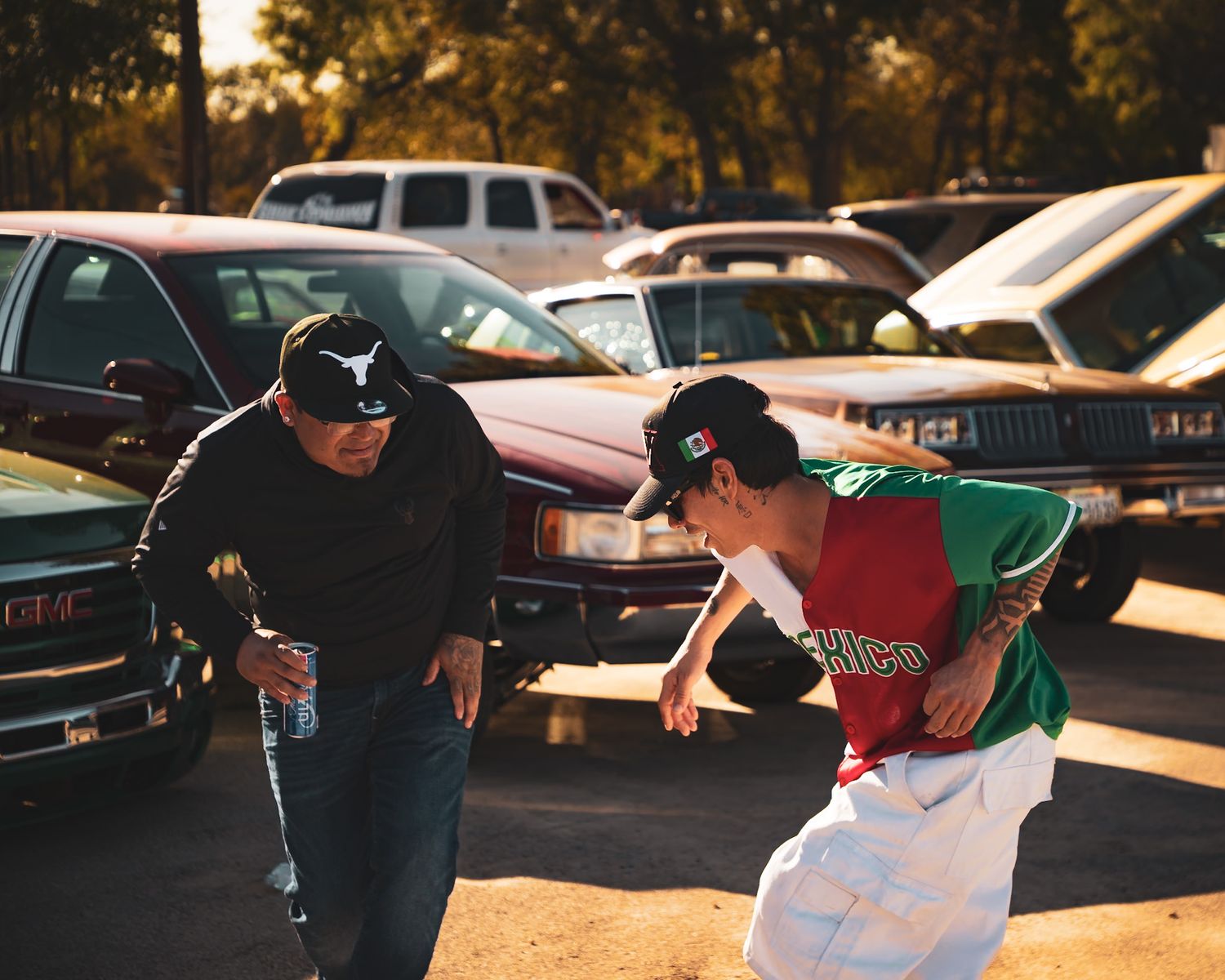 Homies dancing outdoors in front of low riders during golden hour lighting. Captured by a Seguin photographer at grain n glass