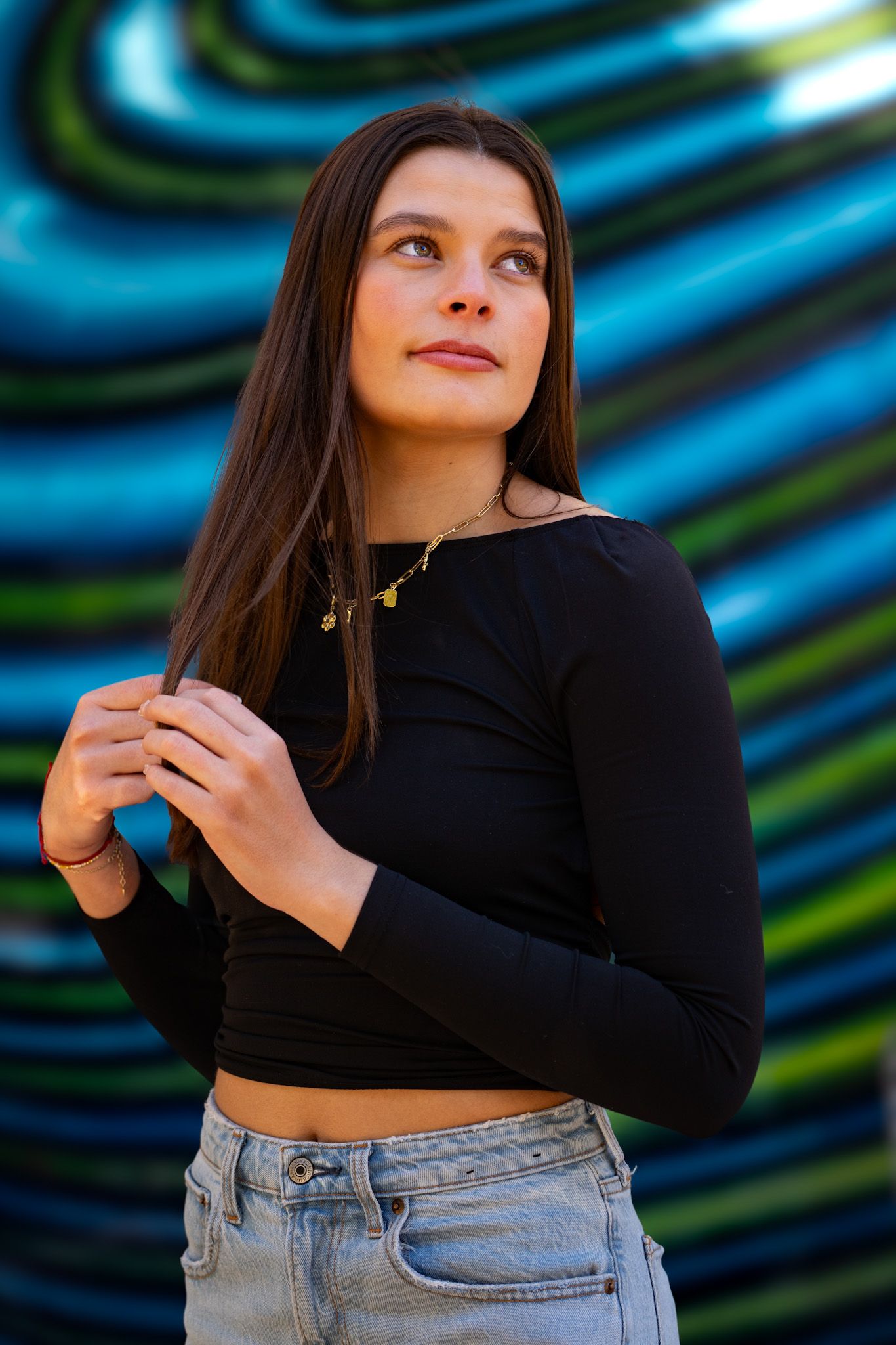 Person in black top poses against vibrant blue and green swirled background.