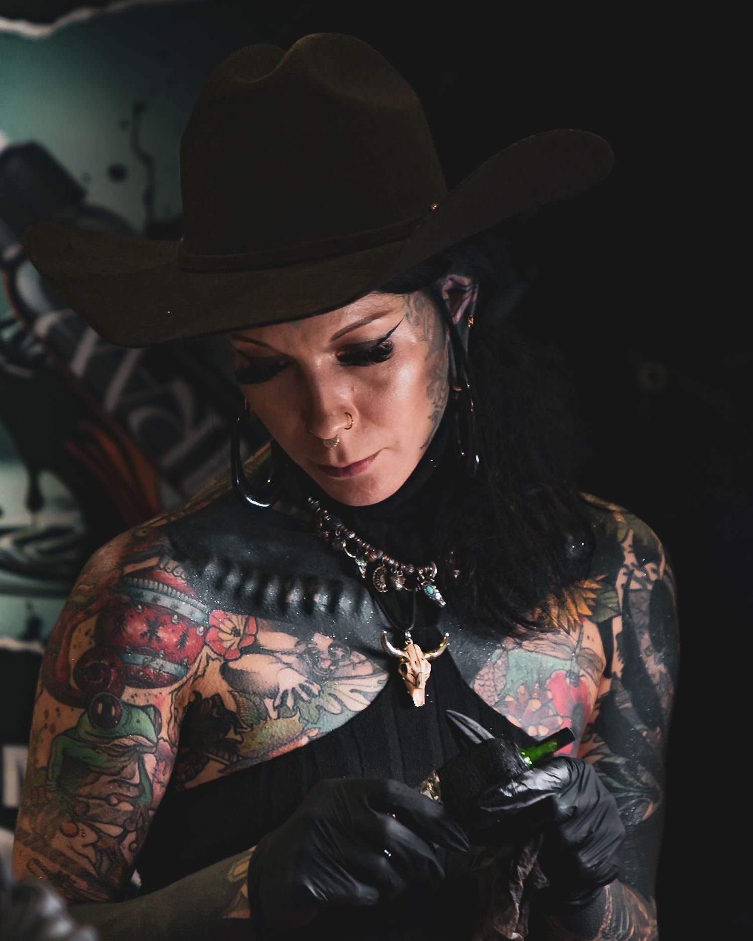 Tattooed artist working in dark lighting with artistic equipment. Captured by a Seguin photographer at grain n glass