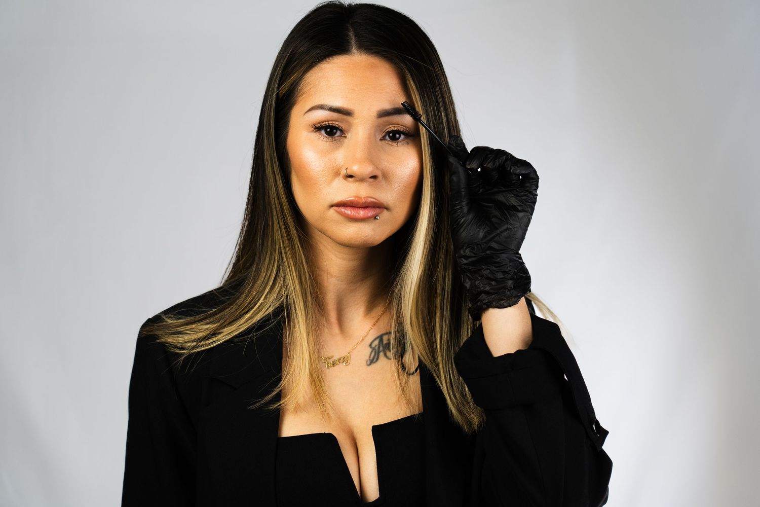 Fashionable pose in black outfit with gloves against studio background.