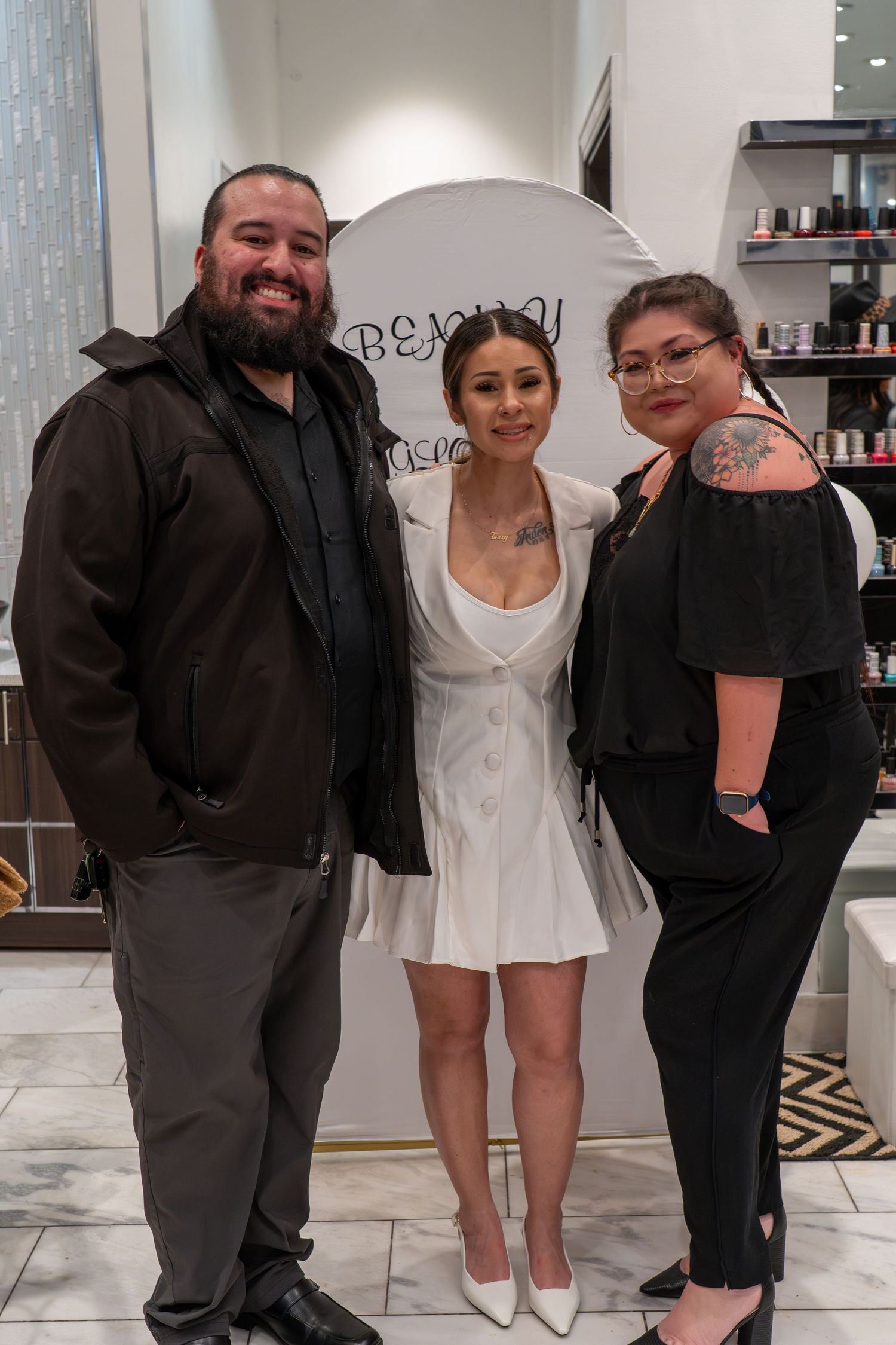 Friends gather for photos in a modern salon space with white walls and retail shelving.