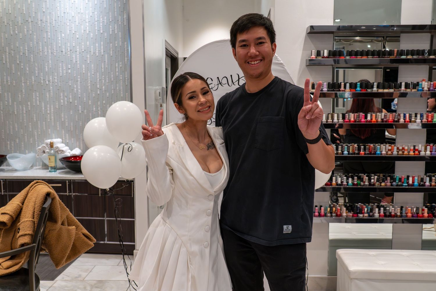 People posing playfully in a modern salon with white decor and product displays.