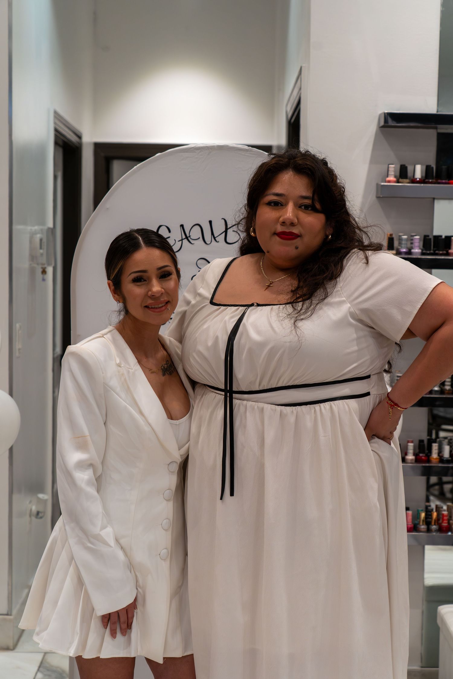 People in coordinated white outfits pose together in a modern salon setting.