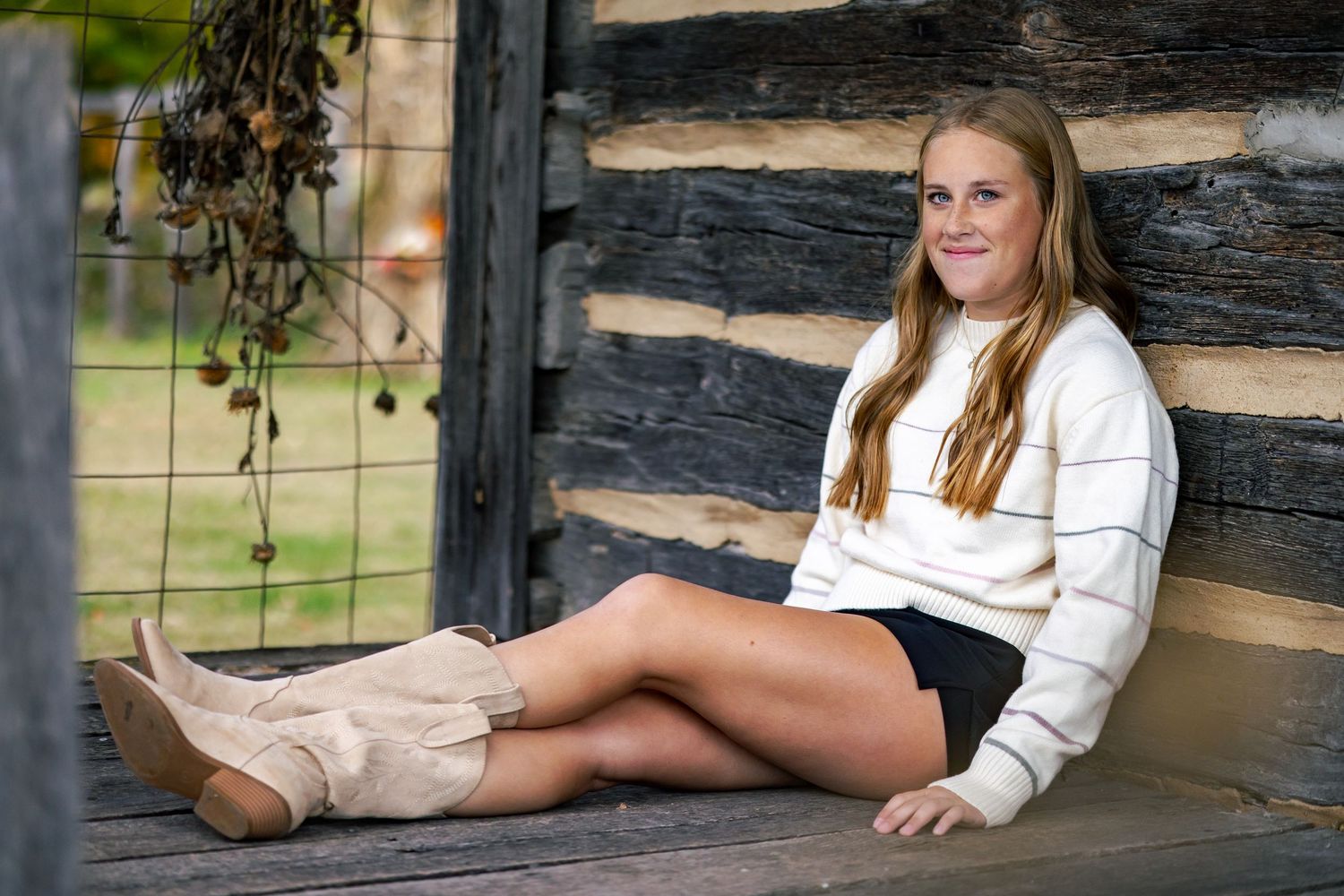 senior girl portrait sitting on historic log cabin porch