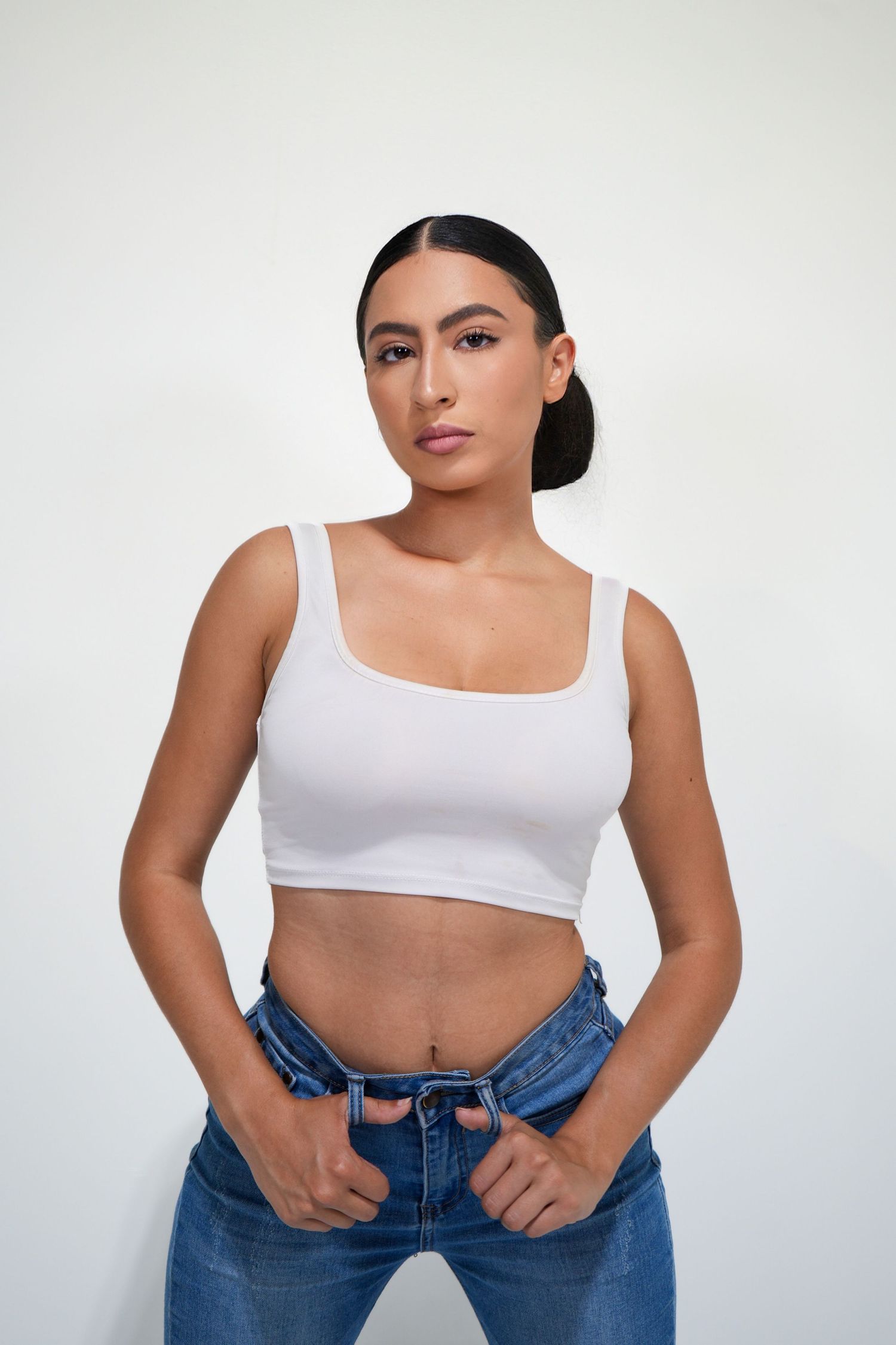 A person in a white crop top and blue jeans poses against a white background in a four-panel photo sequence.