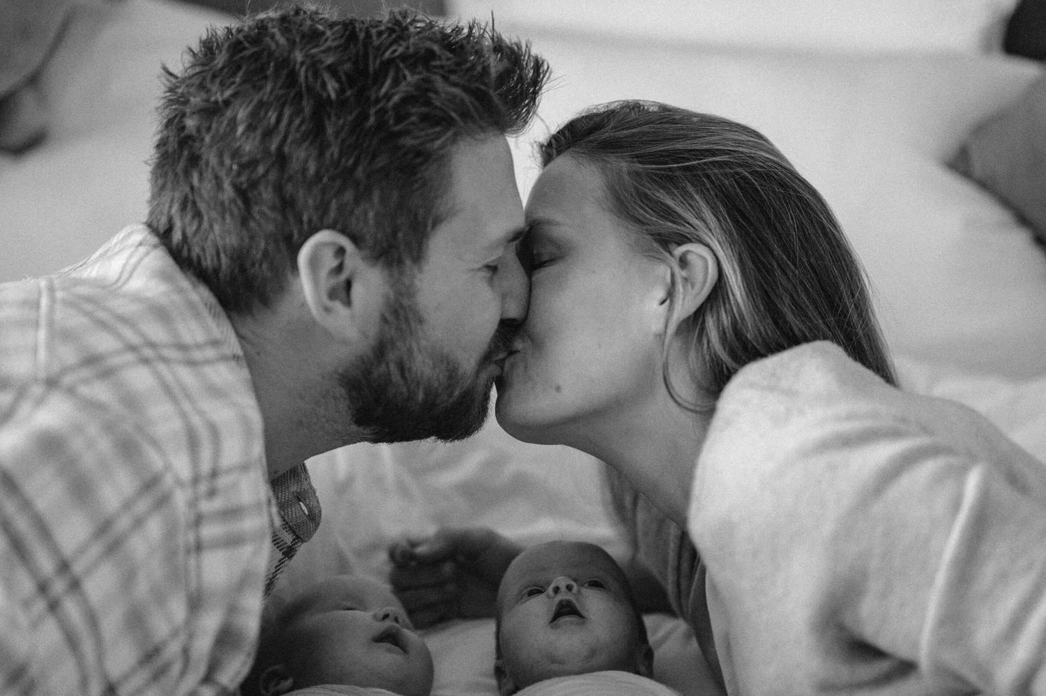 Babyfotografie Zürich Mutter und Vater mit Zwillingen auf Bett Kuss