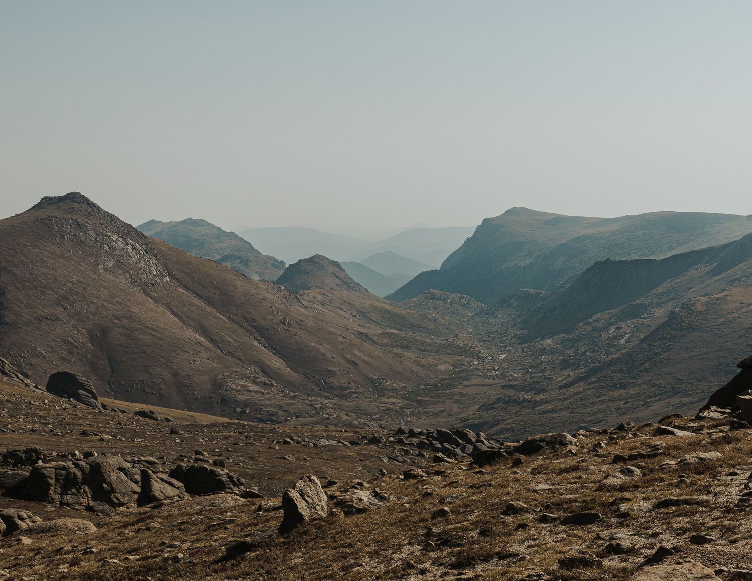Stunning panoramic view of rocky mountain peaks shrouded in mist with multiple connected peaks extending into the horizon.