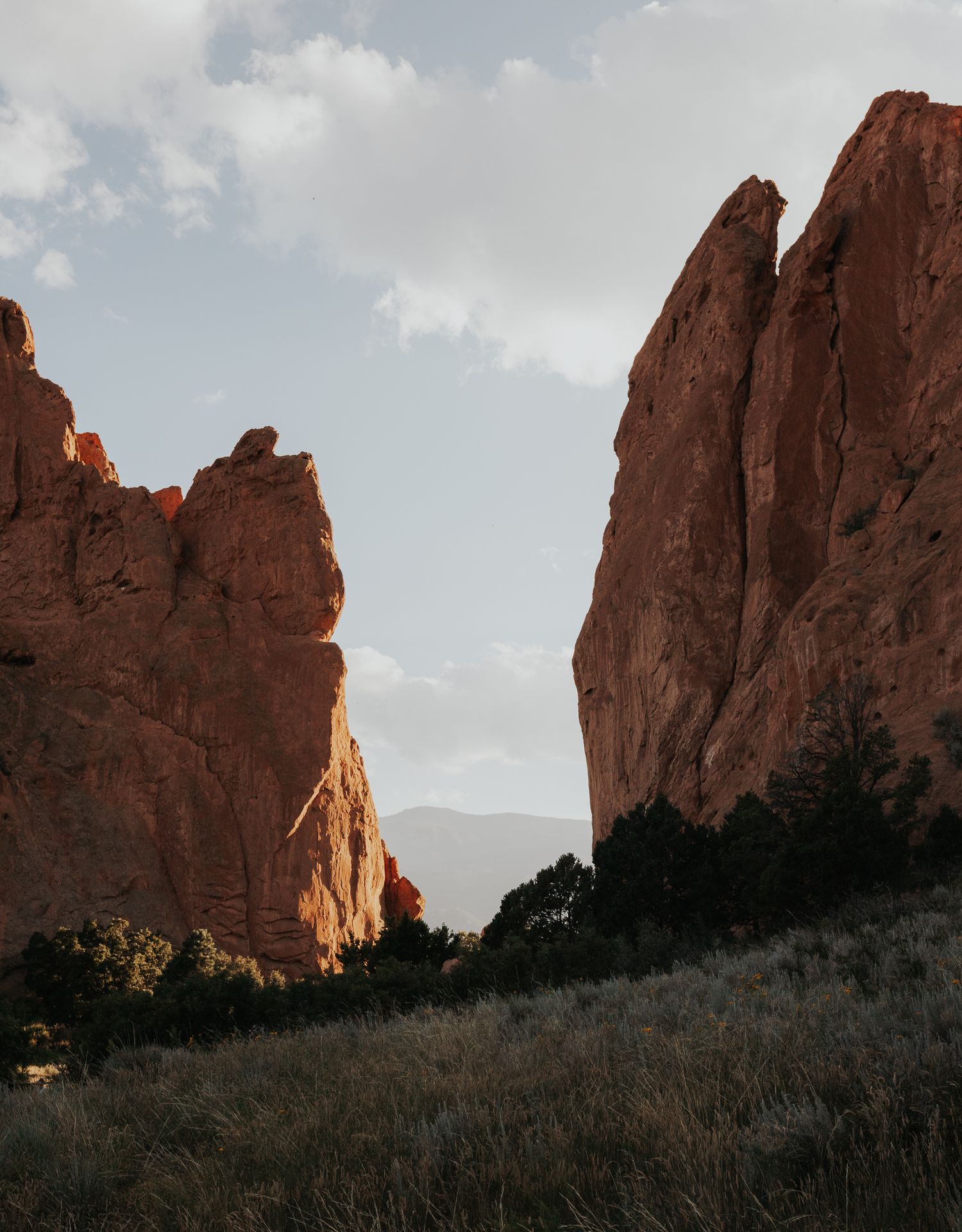 Dramatic view of towering red rock formations at Garden of the Gods in Colorado against a cloudy sky at sunset.