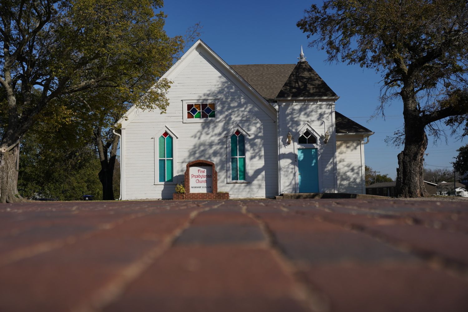 Small white church with turquoise doors and Gothic architecture details.